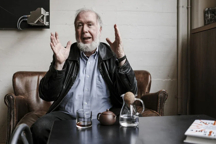 Kevin Kelly gesturing as he talks in his studio